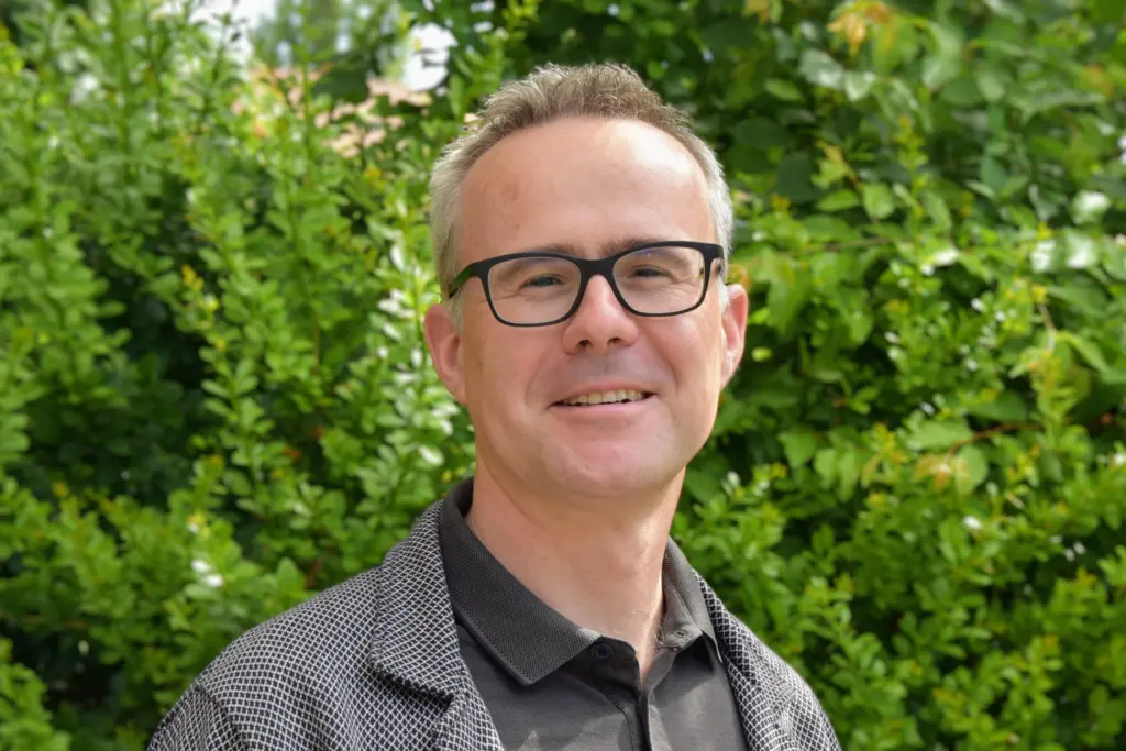 Johannes Zintz von ekin lächelt in die Kamera vor Natur-Hintergrund