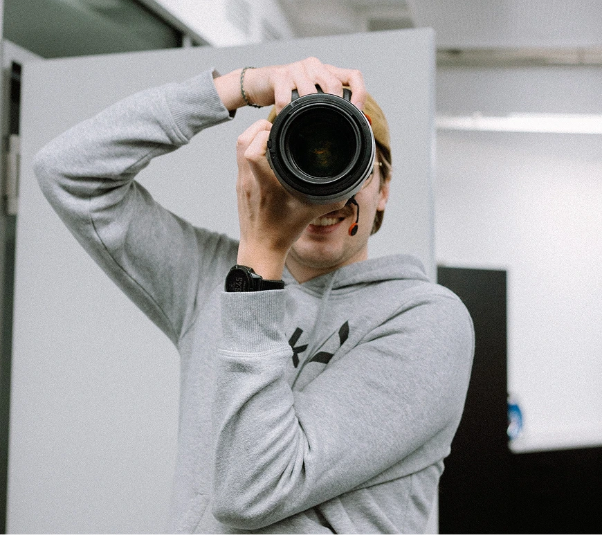 Ein Fotograf von wirdenkenlokal steht mit seiner Kamera in einem Büro und fotografiert in Richtung des Viewers