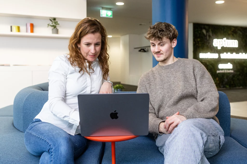 Zwei Kollegen von wirdenkenlokal schauen gemeinsam in einen Laptop bei der Zusammenarbeit
