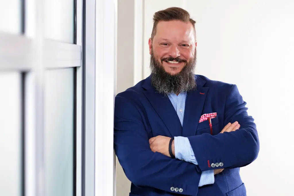 Michael Fröhlich lächelt in die Kamera, mit verschränkten Armen