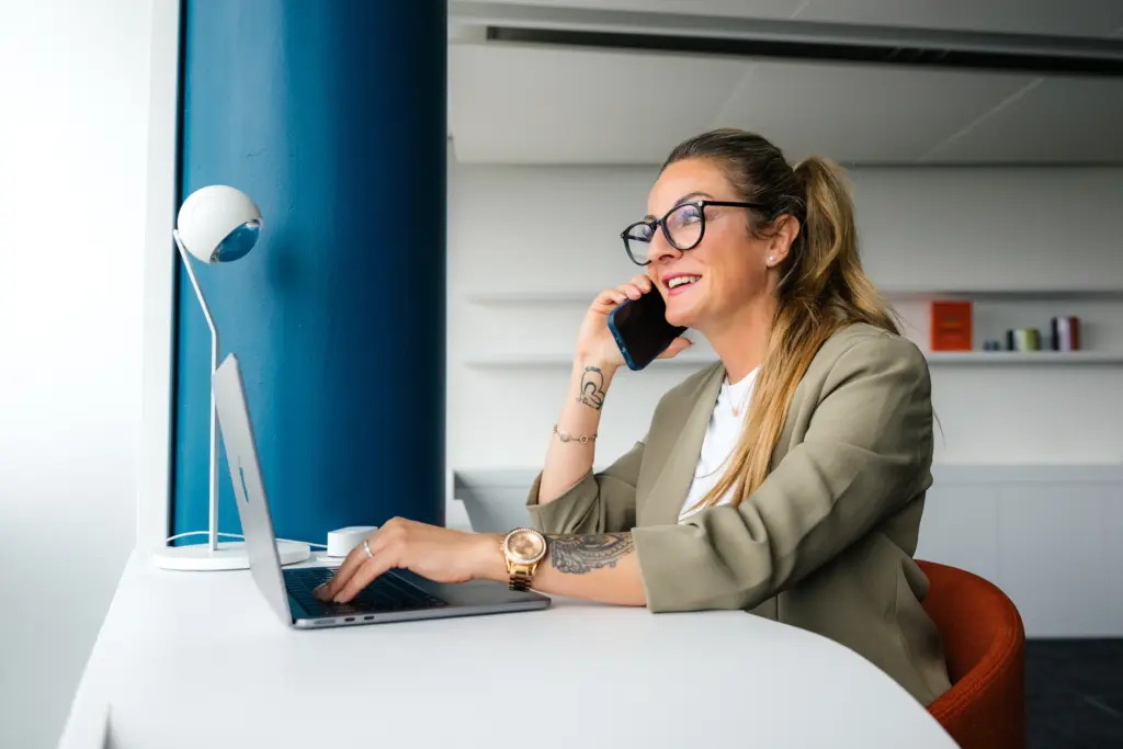 Eine Vertrieblerin sitzt im Büro an ihrem Laptop und telefoniert